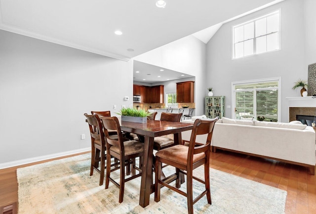 4724 Trademark Trl, Hilliard, OH 43026 - dining room featuring light wood finished floors, a glass covered fireplace, high vaulted ceiling, recessed lighting, and crown molding