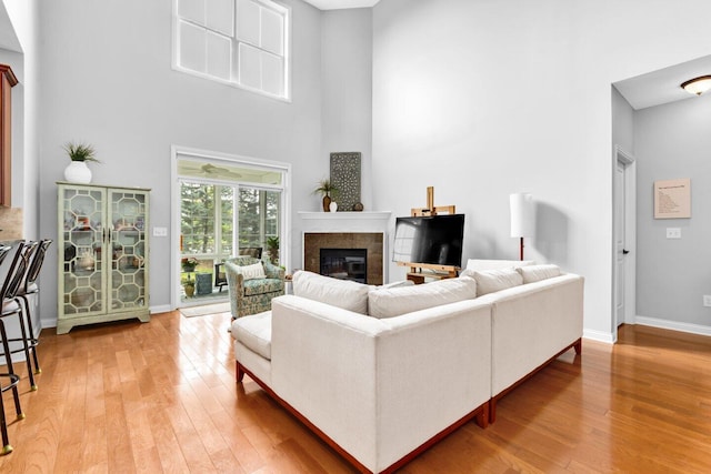 4724 Trademark Trl, Hilliard, OH 43026 - living area with a glass covered fireplace, light wood-style floors, baseboards, and a high ceiling
