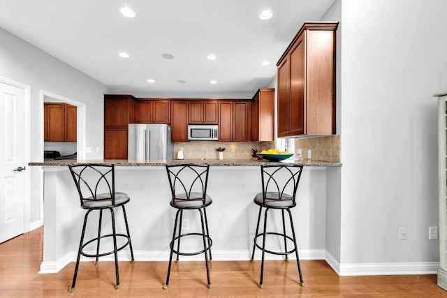 4724 Trademark Trl, Hilliard, OH 43026 - kitchen with appliances with stainless steel finishes, a peninsula, light stone counters, a breakfast bar, and recessed lighting