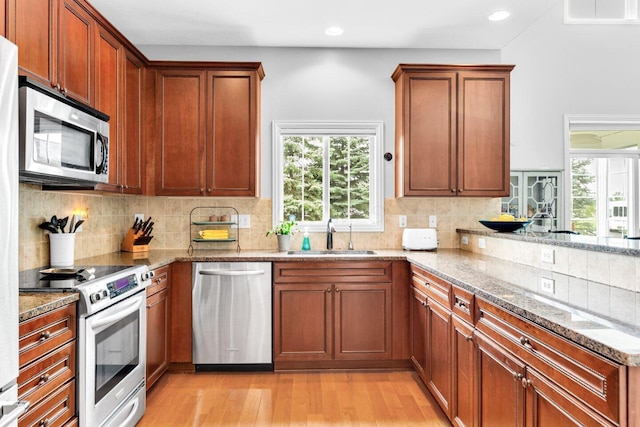 4724 Trademark Trl, Hilliard, OH 43026 - kitchen featuring appliances with stainless steel finishes, a sink, light stone countertops, light wood-type flooring, and healthy amount of natural light