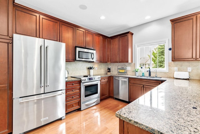 4724 Trademark Trl, Hilliard, OH 43026 - kitchen with stainless steel appliances, a sink, light stone countertops, light wood finished floors, and backsplash