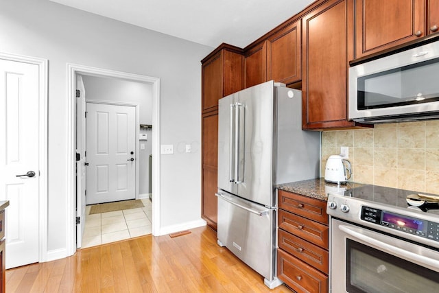 4724 Trademark Trl, Hilliard, OH 43026 - kitchen featuring appliances with stainless steel finishes, backsplash, light wood-style flooring, baseboards, and dark stone countertops