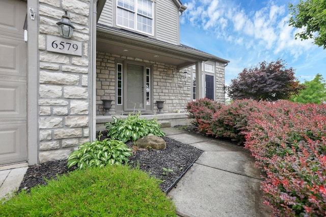 6579 Clay Ct E, Canal Winchester, OH 43110 - doorway to property with stone siding, a porch, and a garage