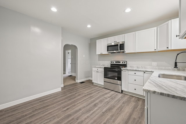 45 S Main St, New Holland, OH 43145 - kitchen with appliances with stainless steel finishes, a sink, arched walkways, light wood-type flooring, and recessed lighting