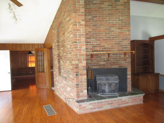 470 Beacon Rd, Newark, OH 43055 - unfurnished living room with wood finished floors, lofted ceiling, a wood stove, track lighting, and wood walls