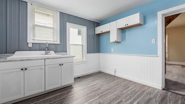 64 W Harrison St, Newark, OH 43055 - kitchen featuring white cabinets, light wood-type flooring, light countertops, wainscoting, and wood walls