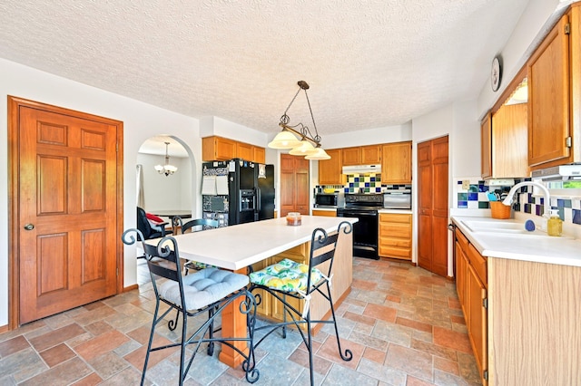 5138 Eastbend Dr, Canal Winchester, OH 43110 - kitchen featuring black appliances, under cabinet range hood, light countertops, arched walkways, and stone tile floors