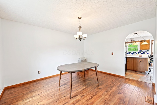 5138 Eastbend Dr, Canal Winchester, OH 43110 - dining area with a chandelier, light wood-style flooring, arched walkways, and a textured ceiling