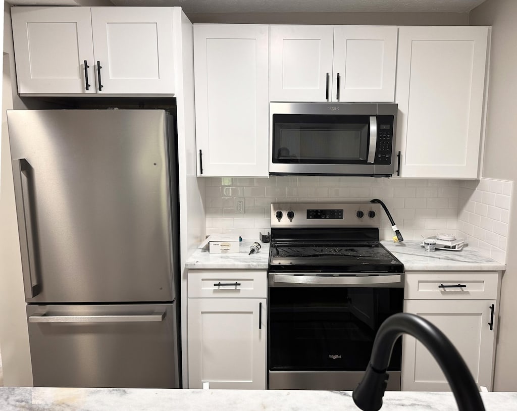 2016 Queensgate Ln, Columbus, OH 43235 - kitchen featuring stainless steel appliances, white cabinetry, tasteful backsplash, and light stone countertops