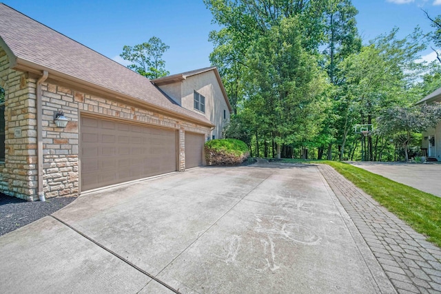 7788 Boylston Ct, Dublin, OH 43016 - view of property exterior with driveway, stone siding, roof with shingles, a garage, and stucco siding