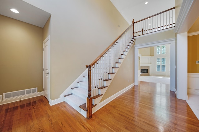 7788 Boylston Ct, Dublin, OH 43016 - stairs featuring wood finished floors, a fireplace, a towering ceiling, and recessed lighting