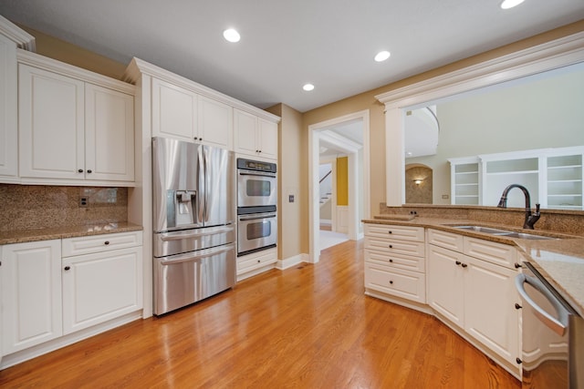 7788 Boylston Ct, Dublin, OH 43016 - kitchen with appliances with stainless steel finishes, light wood-type flooring, white cabinetry, light stone counters, and decorative backsplash