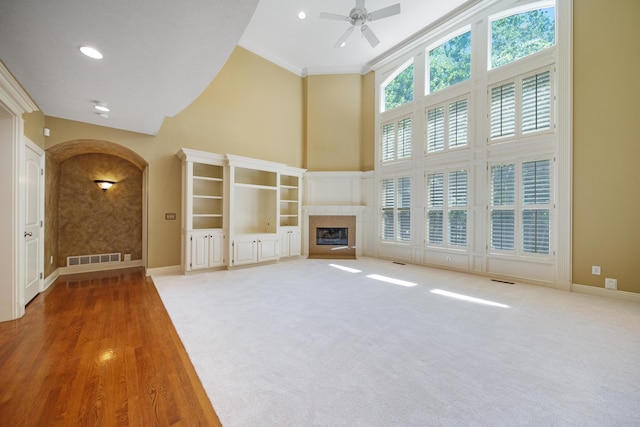 7788 Boylston Ct, Dublin, OH 43016 - unfurnished living room with high vaulted ceiling, arched walkways, a ceiling fan, a glass covered fireplace, and crown molding