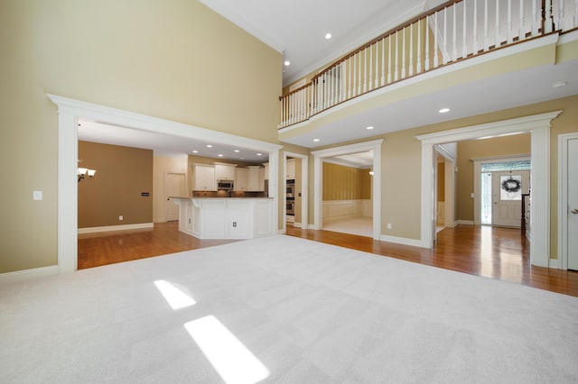 7788 Boylston Ct, Dublin, OH 43016 - unfurnished living room with light carpet, a high ceiling, a chandelier, light wood-style floors, and recessed lighting