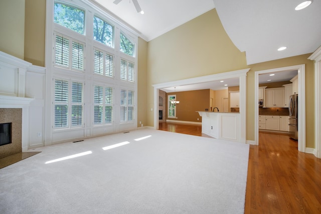 7788 Boylston Ct, Dublin, OH 43016 - unfurnished living room featuring high vaulted ceiling, a high end fireplace, ornamental molding, ceiling fan, and light wood-style floors