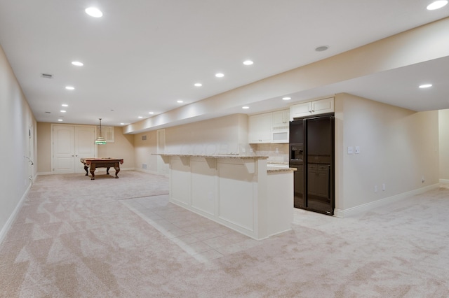 7788 Boylston Ct, Dublin, OH 43016 - kitchen with light carpet, black refrigerator with ice dispenser, light stone counters, recessed lighting, and white microwave