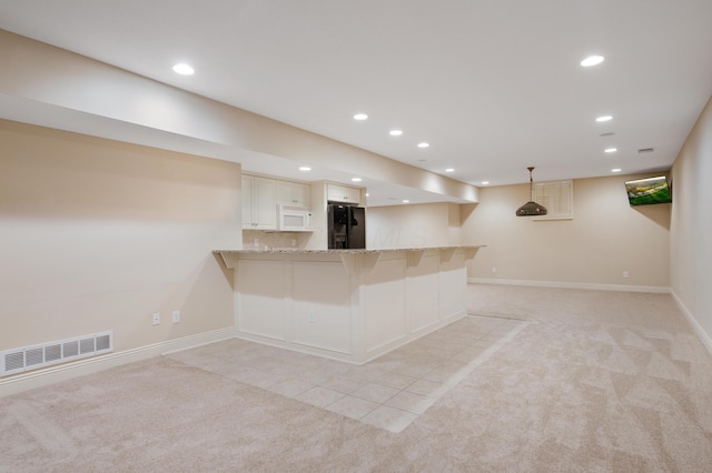 7788 Boylston Ct, Dublin, OH 43016 - kitchen with black fridge, white microwave, light carpet, light stone countertops, and recessed lighting