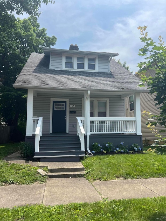 1476 N 6th St, Columbus, OH 43201 - bungalow-style home featuring covered porch, a chimney, a front yard, and roof with shingles