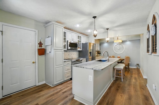 6235 Hampton Green Pl Unit 5B, Dublin, OH 43016 - kitchen with stainless steel appliances, dark wood-type flooring, backsplash, a kitchen bar, and a textured ceiling