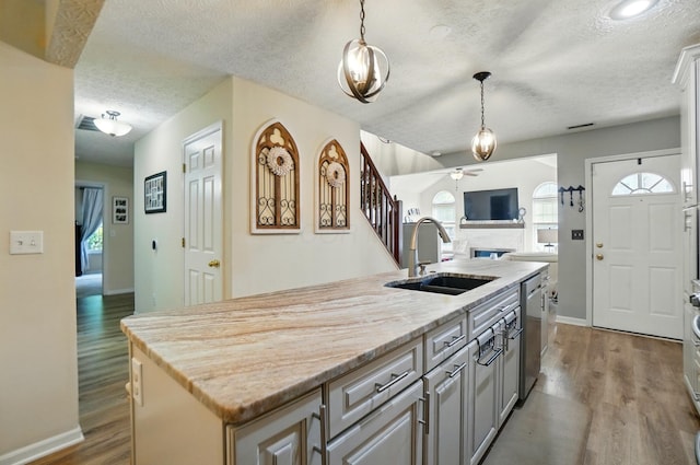6235 Hampton Green Pl Unit 5B, Dublin, OH 43016 - kitchen featuring a fireplace, a kitchen island with sink, ceiling fan, stainless steel dishwasher, and a textured ceiling