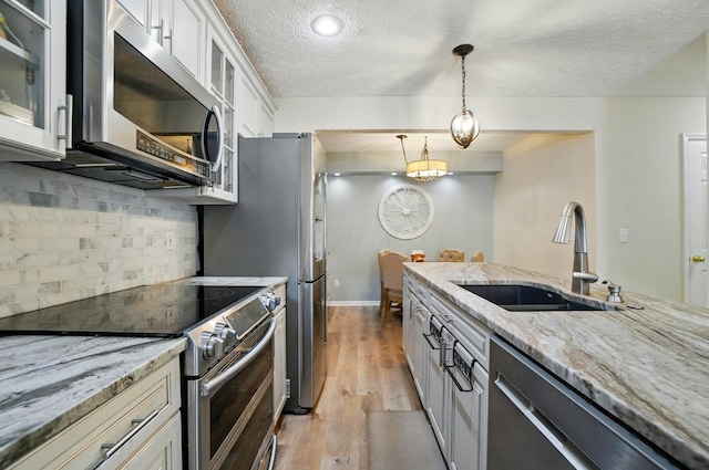 6235 Hampton Green Pl Unit 5B, Dublin, OH 43016 - kitchen featuring appliances with stainless steel finishes, tasteful backsplash, light stone countertops, light wood-style floors, and hanging light fixtures