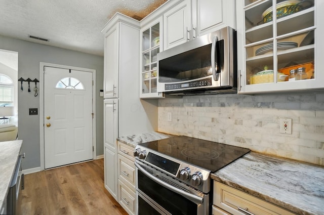 6235 Hampton Green Pl Unit 5B, Dublin, OH 43016 - kitchen with appliances with stainless steel finishes, glass insert cabinets, white cabinets, wood finished floors, and a textured ceiling
