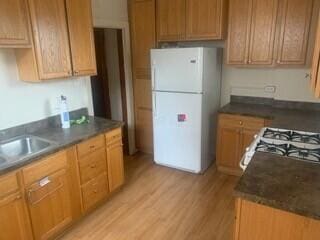 384 E 17th Ave, Columbus, OH 43201 - kitchen with freestanding refrigerator, light wood-style floors, range with gas cooktop, a sink, and dark countertops