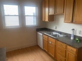 384 E 17th Ave, Columbus, OH 43201 - kitchen featuring stainless steel dishwasher, a sink, light wood-style floors, dark countertops, and brown cabinets