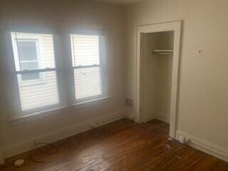 384 E 17th Ave, Columbus, OH 43201 - unfurnished bedroom with wood finished floors, baseboards, and a closet