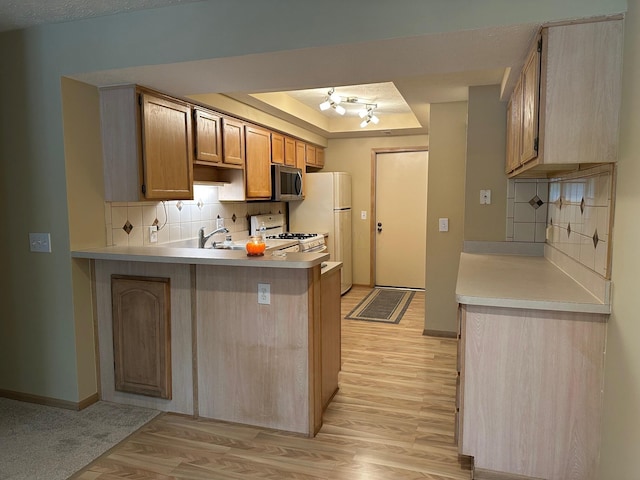 2328 Willowside Ln, Grove City, OH 43123 - kitchen featuring white appliances, light wood-style floors, a raised ceiling, a peninsula, and decorative backsplash
