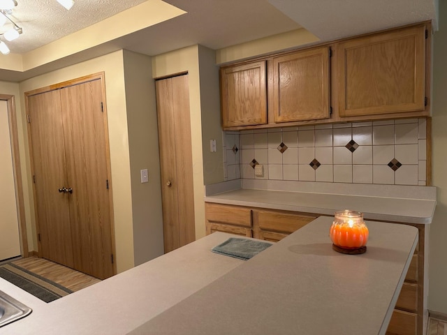 2328 Willowside Ln, Grove City, OH 43123 - kitchen featuring backsplash, light countertops, a textured ceiling, and brown cabinetry