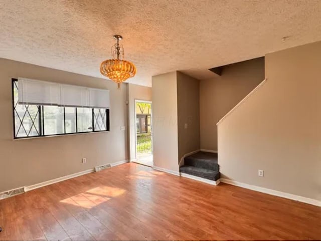 991 Hidden Acres Ct, Columbus, OH 43224 - unfurnished living room with wood finished floors, a textured ceiling, stairs, and a chandelier