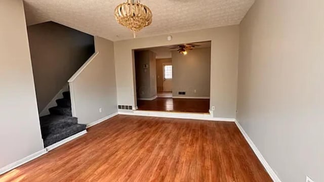 991 Hidden Acres Ct, Columbus, OH 43224 - unfurnished living room with wood finished floors, stairway, a chandelier, a ceiling fan, and a textured ceiling