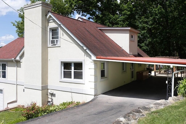 45 Shady Ln Unit 552On, Waverly, OH 45690 - view of front of property featuring a chimney, roof with shingles, a carport, asphalt driveway, and stucco siding