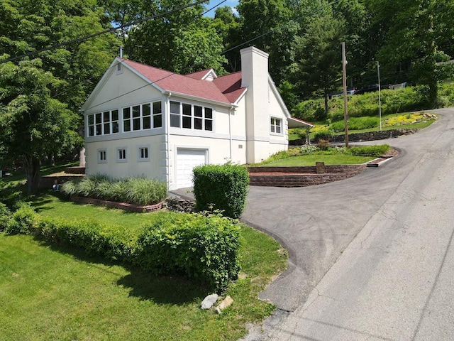 45 Shady Ln Unit 552On, Waverly, OH 45690 - view of front of house featuring stucco siding, a chimney, an attached garage, driveway, and a front lawn