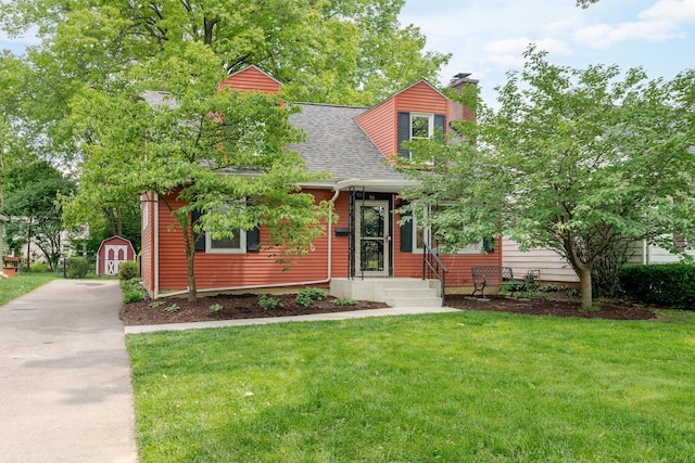 98 N Chesterfield Rd, Columbus, OH 43209 - view of front of house with a chimney, a shingled roof, a front yard, and a storage shed