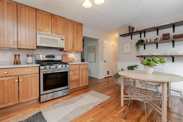 98 N Chesterfield Rd, Columbus, OH 43209 - kitchen featuring white microwave, stainless steel gas stove, light countertops, light wood finished floors, and a wainscoted wall