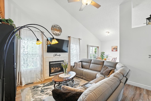 906 Linkfield Dr, Columbus, OH 43085 - living area featuring light wood finished floors, a ceiling fan, a tiled fireplace, and high vaulted ceiling