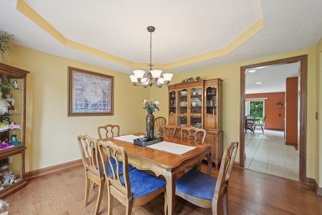 13946 Bainwick Dr NW, Pickerington, OH 43147 - dining room with a chandelier, a raised ceiling, and light wood-style flooring
