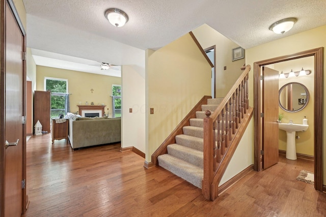 13946 Bainwick Dr NW, Pickerington, OH 43147 - staircase with a textured ceiling, a ceiling fan, wood finished floors, and a fireplace