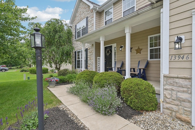 13946 Bainwick Dr NW, Pickerington, OH 43147 - view of exterior entry with stone siding, a porch, and a yard