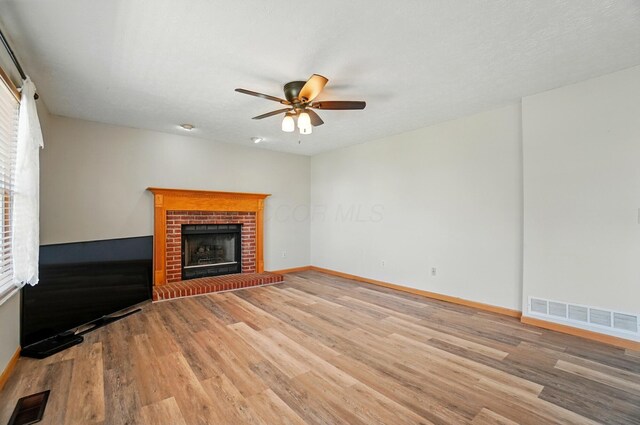 8578 Bivouac Pl, Galloway, OH 43119 - unfurnished living room with light wood-style floors, ceiling fan, a fireplace, and healthy amount of natural light