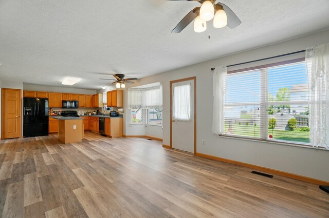 8578 Bivouac Pl, Galloway, OH 43119 - kitchen featuring black appliances, ceiling fan, light wood-style flooring, a textured ceiling, and a center island