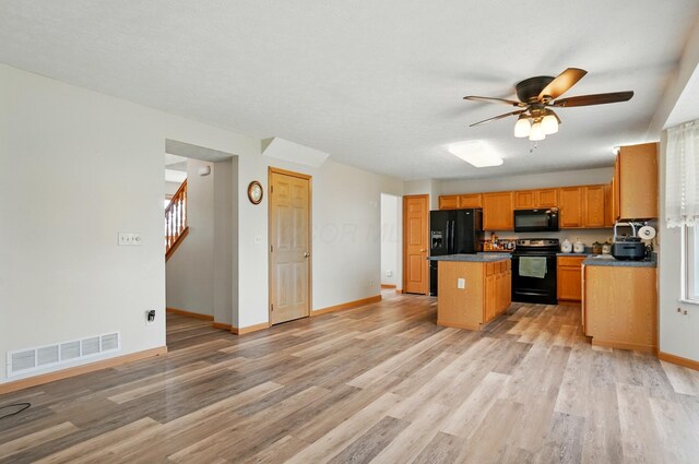 8578 Bivouac Pl, Galloway, OH 43119 - kitchen featuring black appliances, light wood-type flooring, a kitchen island, a ceiling fan, and dark countertops