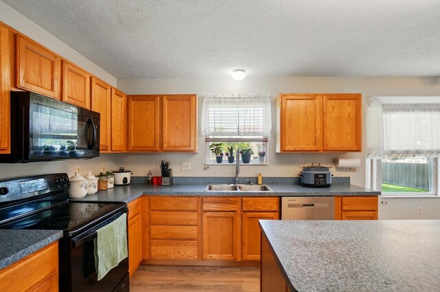8578 Bivouac Pl, Galloway, OH 43119 - kitchen with black appliances, a textured ceiling, light wood-style flooring, dark countertops, and brown cabinets