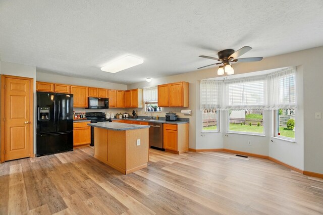 8578 Bivouac Pl, Galloway, OH 43119 - kitchen featuring black appliances, light wood-style floors, a kitchen island, ceiling fan, and a textured ceiling