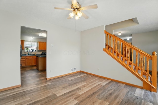 8578 Bivouac Pl, Galloway, OH 43119 - unfurnished living room featuring wood finished floors, ceiling fan, and stairway