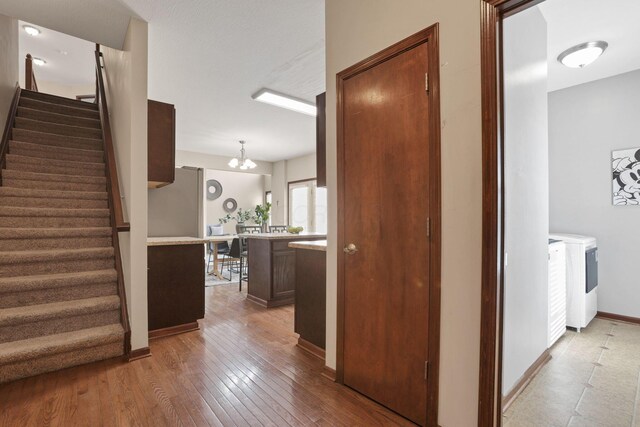 101 Stirling Way, Etna, OH 43062 - hallway featuring washer and clothes dryer, stairway, wood-type flooring, and a chandelier