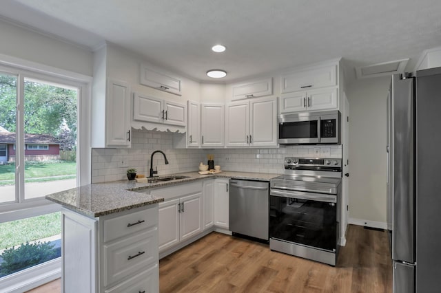 2870 Hamilton Ave, Columbus, OH 43224 - kitchen featuring stainless steel appliances, white cabinetry, light stone countertops, backsplash, and light wood-style flooring