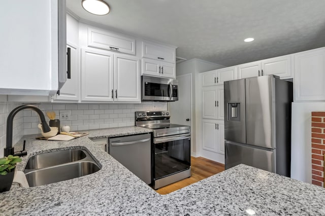 2870 Hamilton Ave, Columbus, OH 43224 - kitchen featuring appliances with stainless steel finishes, white cabinetry, light wood finished floors, light stone countertops, and backsplash
